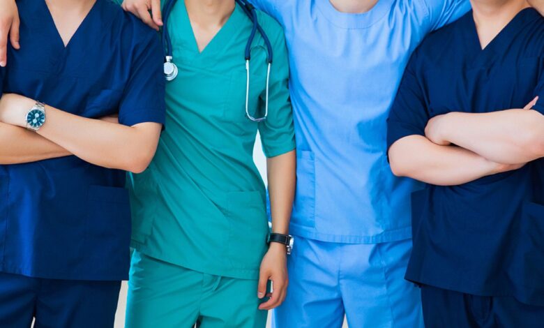 A group of 4 doctors wearing different colors of medical scrubs